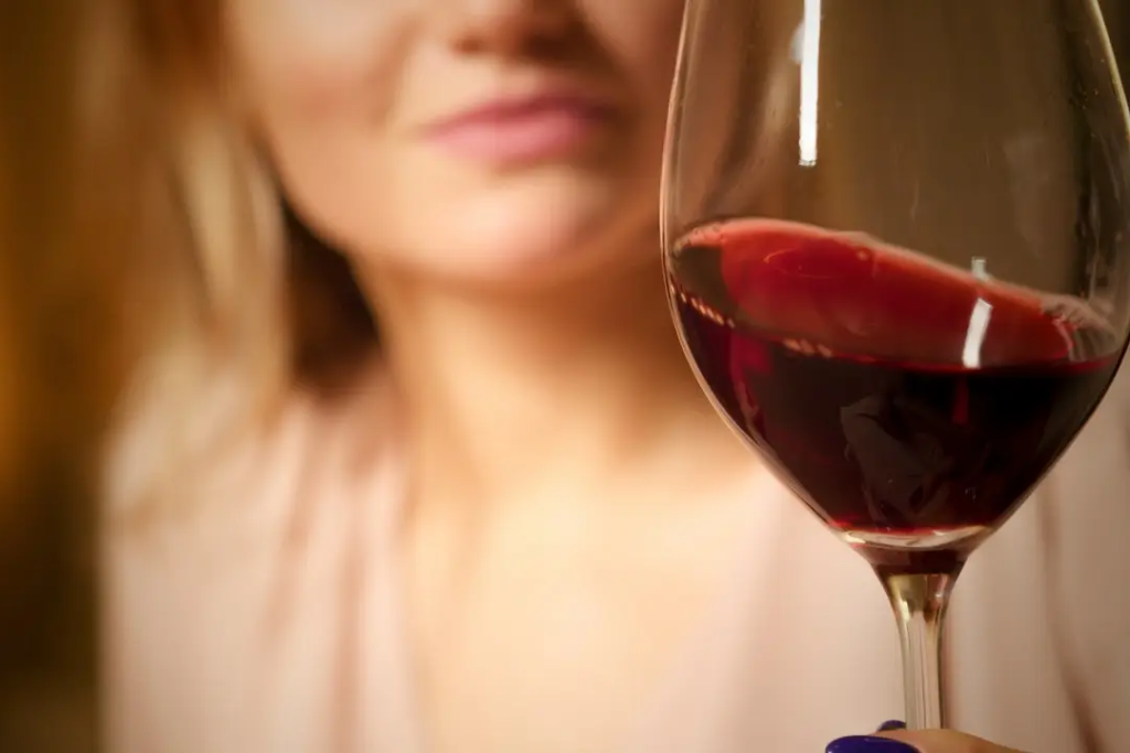 woman holding a wine glass filled with red wine